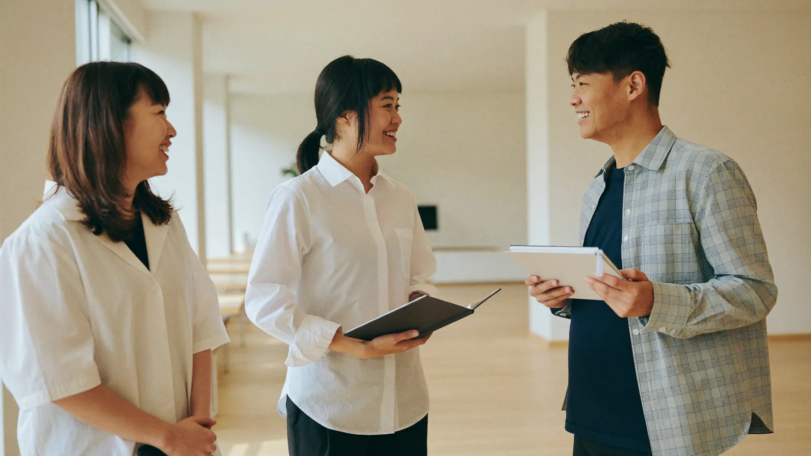 明るいオフィスで談笑する若手社員たち
